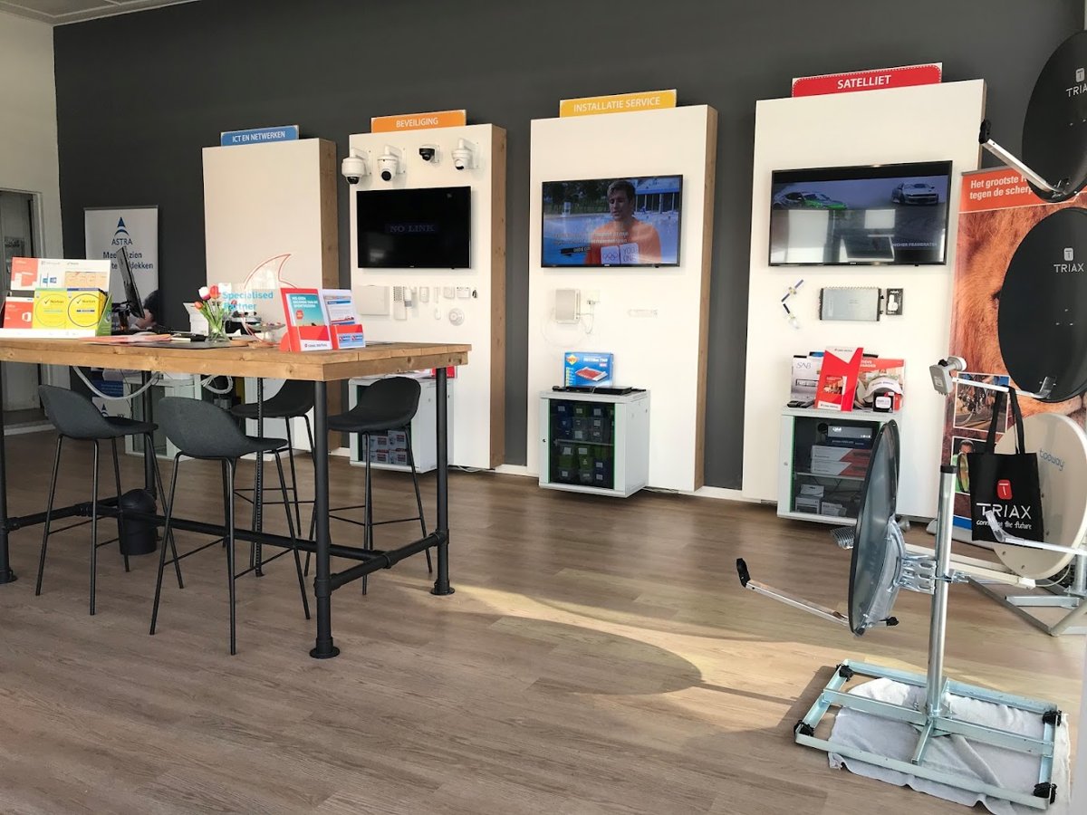 Binnen in de winkel: gesprekstafel en demonstratiepanelen voor ICT, beveiliging en televisie